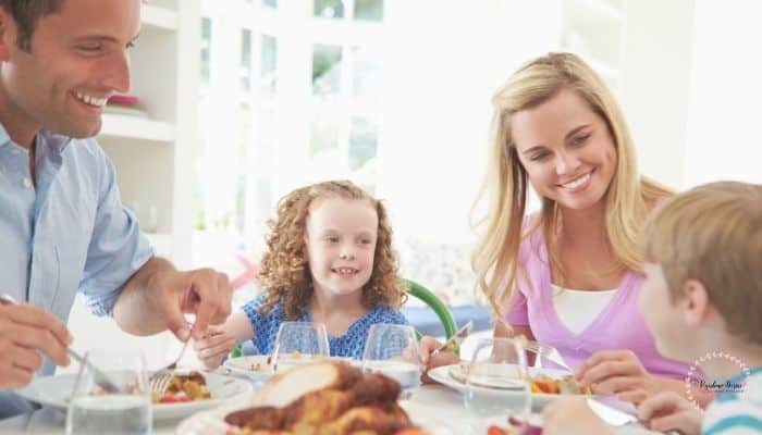 A Family sitting on a dining table sharing a happy mealtime together. 
