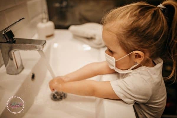 A toddler girl washing her hands. 